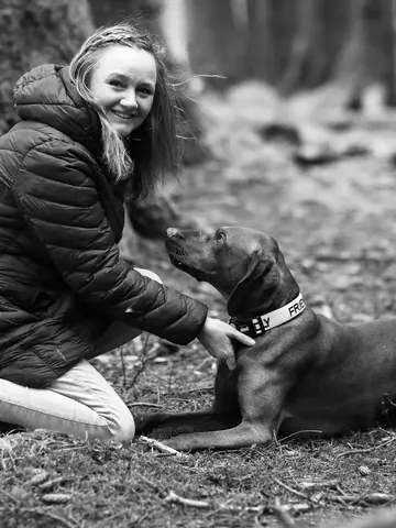 Emma Kneale kneeling in woodland with her dog Bentley