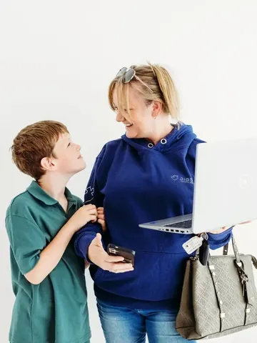Emma Kneale chatting with her son Xavi while holding a laptop and handbag