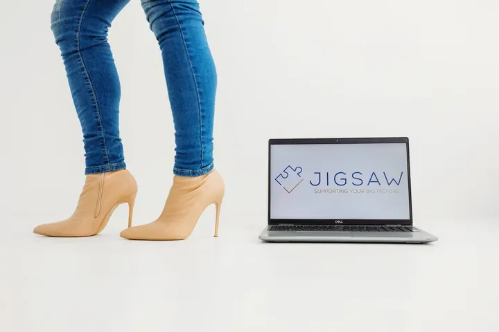 Open laptop showing the Jigsaw logo beside a pair of heeled shoes, ready for a Power Hour