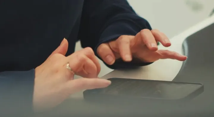 Close-up of hands working on a phone at a desk, catching up on the books